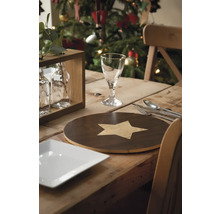 Masa festivă din lemn cu farfurie, tacâmuri, pahar, suport de farfurie și brad de Crăciun în fundal