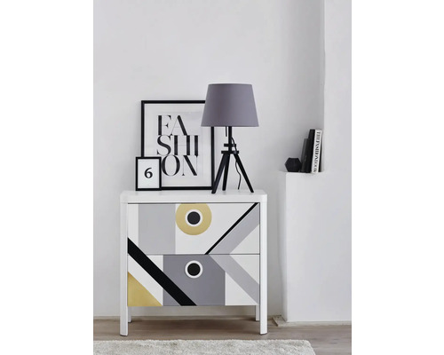 Noptieră cu model geometric, lampă de masă și decorațiuni pe o comodă albă
