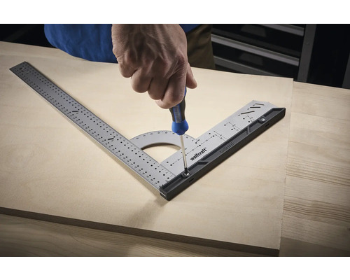 Artizanul înșurubează un unghi multifuncțional pe o scândură de lemn cu o șurubelniță