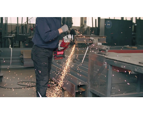 Un bărbat taie o bucată de metal cu un polizor unghiular.