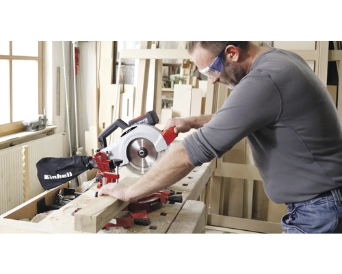 Un bărbat taie o scândură de lemn cu un ferăstrău Einhell de tăiat în unghi.