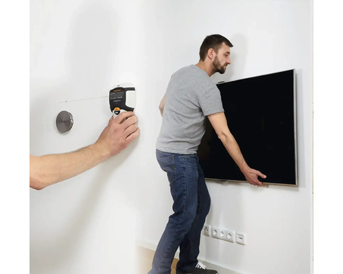 Un bărbat montează un televizor pe perete cu ajutorul unui boloboc.