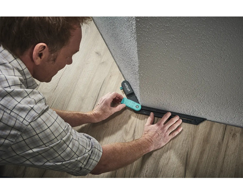 Un bărbat folosește un șablon de marcare Wolfcraft pentru a așeza laminatul.