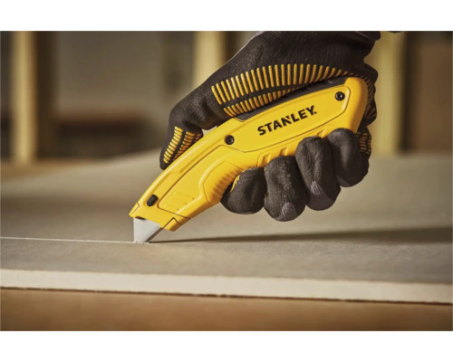 Siglă Stanley. Mână cu mănușă taie o placă cu un cutter.