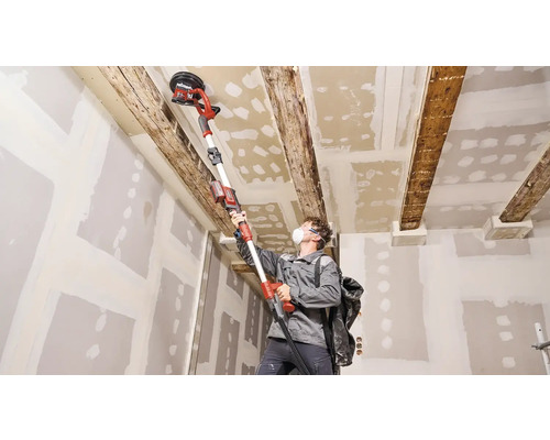 Bărbat șlefuiește tavanul cu o mașină de șlefuit tavanul într-o cameră