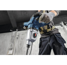 Un muncitor în construcții operează un ciocan demolator.