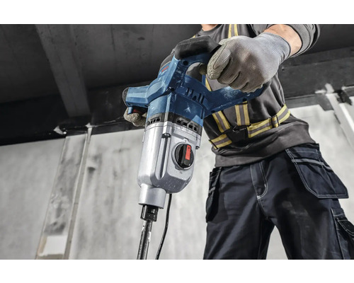 Un muncitor în construcții operează un ciocan demolator.