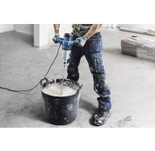 Artizan amestecând mortar cu un mixer electric într-o găleată.