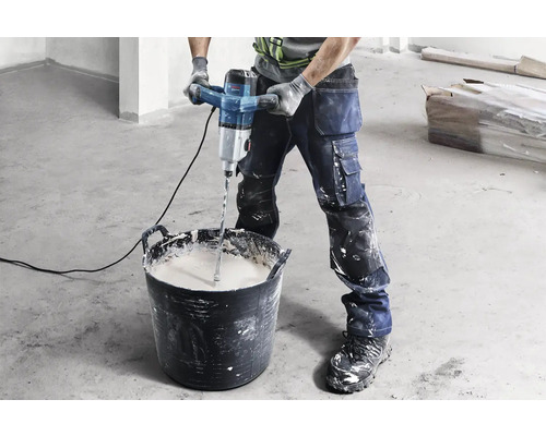 Artizan amestecând mortar cu un mixer electric într-o găleată.