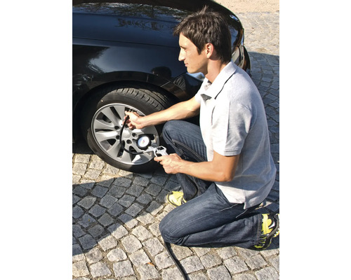 Bărbat umflă o anvelopă de mașină cu un manometru.