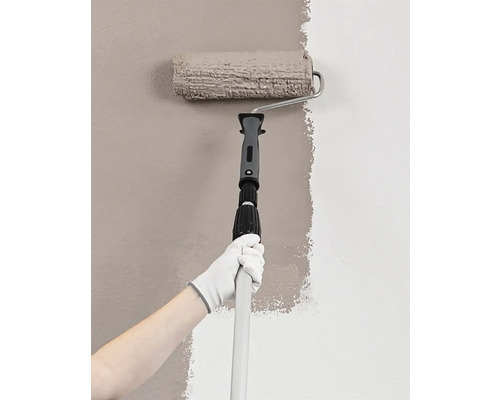Persoană care vopsește un perete cu trafalet și tijă telescopică
