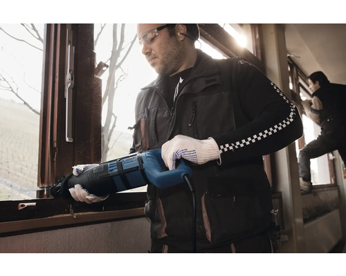 Un meșter demontează o fereastră cu un ferăstrău electric.