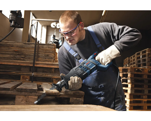 Un bărbat taie o scândură de lemn cu un fierăstrău electric.