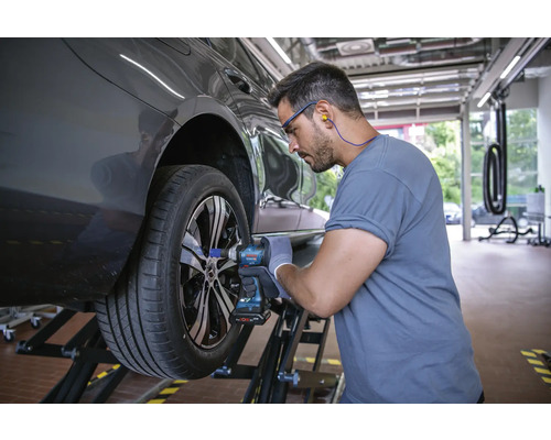 Un mecanic schimbă o roată cu o cheie de impact cu acumulator.