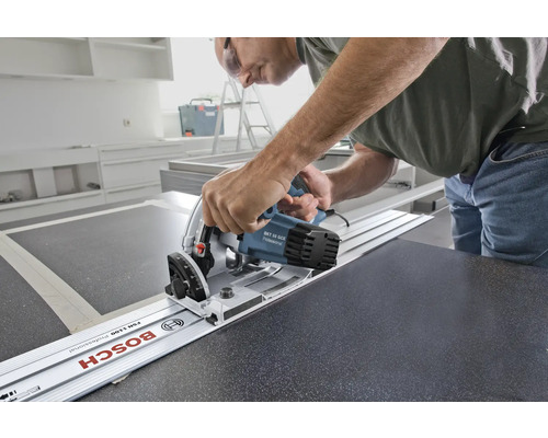 Meșter folosind un fierăstrău circular portabil cu șină de ghidare pentru a tăia un blat de lucru