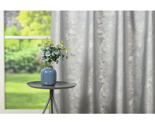 Perdea decorativă cu model floral lângă o masă cu vază de flori.