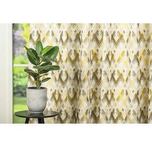 Cortină decorativă cu model geometric lângă o plantă de interior pe o masă.