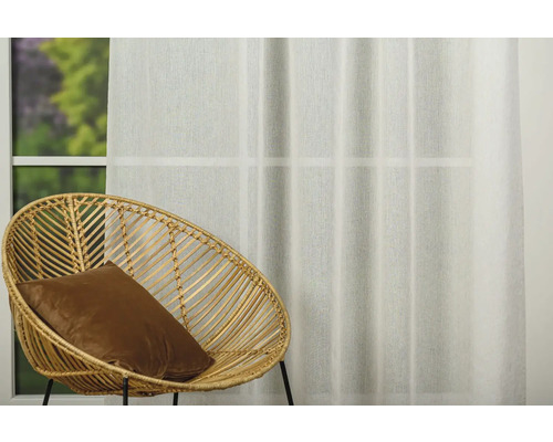 Interior decorativ cu fotoliu din ratan și perdea în fața unei ferestre