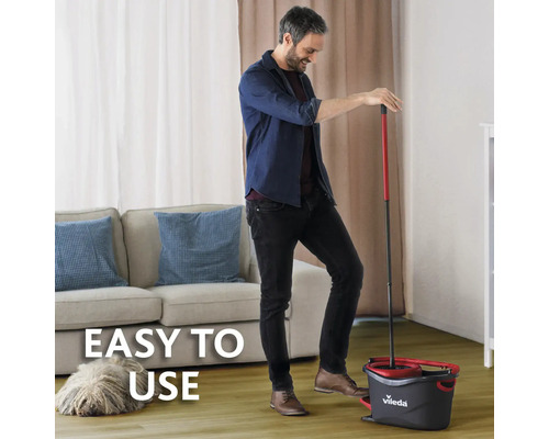 Un bărbat folosește un set de mop Vileda într-un living pentru curățarea podelelor.