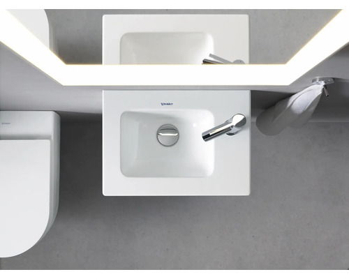 Vedere de sus a unei băi cu chiuvetă, oglindă cu iluminare, prosop și toaletă.