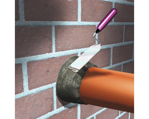 Ilustrație cu o persoană care sigilează o trecere prin perete cu mortar de rosturi