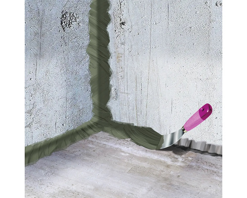 Colțul dintre perete și podea este etanșat cu chit, spatulă cu mâner de lemn