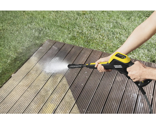 O persoană curăță o terasă din lemn cu un curățător cu presiune marca Kärcher