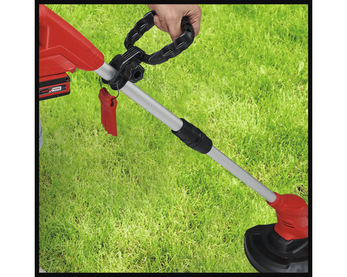 Trimmer de gazon cu acumulator în uz pe un gazon.