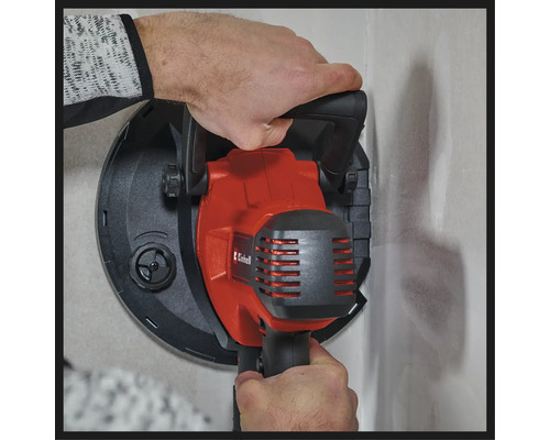 O persoană folosește o șlefuitoare pentru gips-carton Einhell pe un perete.