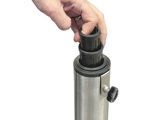 O mână așază o manșon de reducere negru pe un suport metalic pentru o umbrelă de soare.