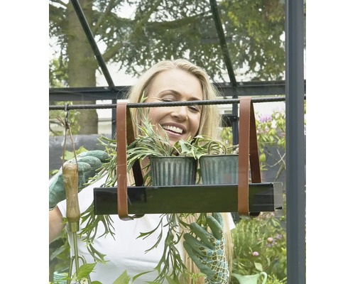 Femeie în seră cu suport suspendat pentru plante cu două plante