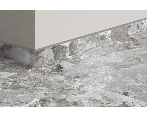 Prim-plan al unei încăperi cu gresie și plintă cu aspect de piatră