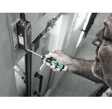 Un bărbat folosește o șurubelniță pentru a strânge un șurub pe o componentă electronică.