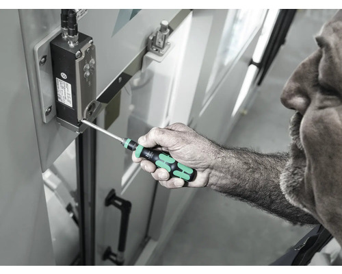 Un bărbat folosește o șurubelniță pentru a strânge un șurub pe o componentă electronică.