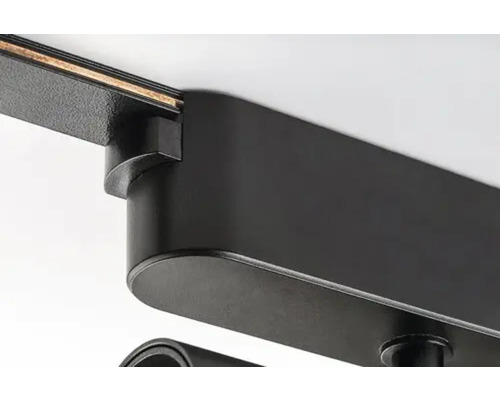 Prim-plan al unui corp de iluminat negru pe șină pe un tavan.