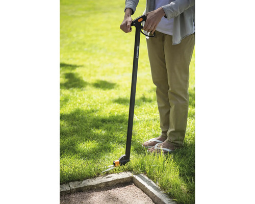 Persoană care folosește o foarfecă de iarbă Fiskars pentru tăierea marginilor gazonului