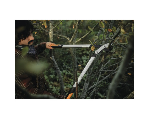 O persoană folosește un foarfece de crengi cu transmisie pentru a tăia crengi.