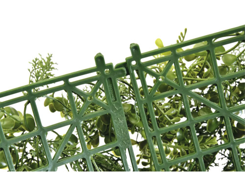 Prim-plan cu o grilă de plastic cu mecanism de fixare și plante decorative verzi.
