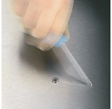 O mână aplică adeziv dintr-o sticlă pe un șurub.