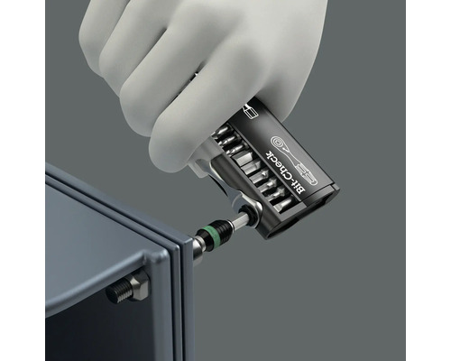 O mână cu mănușă folosește un set de instrumente pentru verificarea biților pe un șurub.