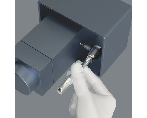 O mână ține o cheie tubulară cu bit de șurubelniță pe un șurub într-o carcasă