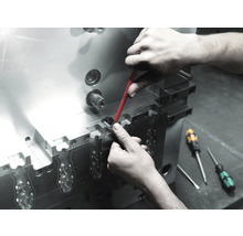 Un muncitor efectuează întreținerea unei scule metalice cu o șurubelniță.