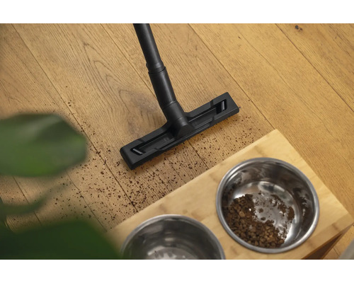 Aspirator care curăță podeaua lângă castronul cu hrană