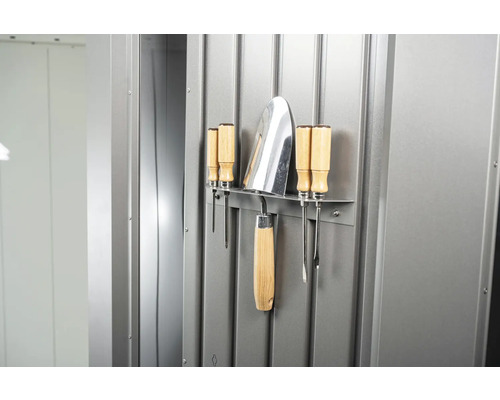 Unelte de grădină precum o lopată și șurubelnițe fixate pe un perete metalic