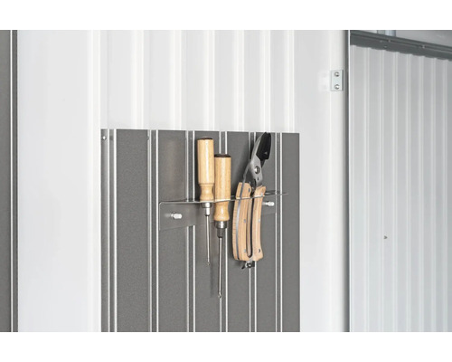 Panou de scule cu șurubelnițe și foarfece de grădină pe un perete alb.