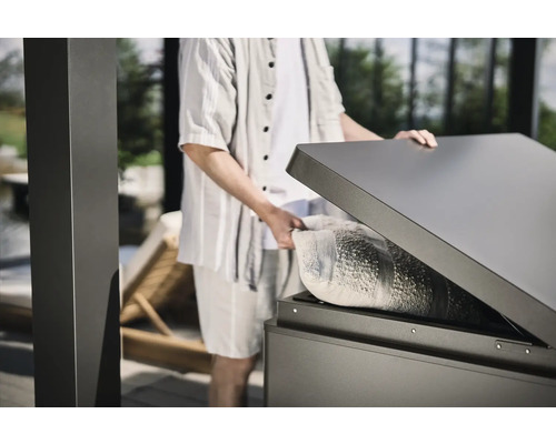 Persoană care deschide o cutie de depozitare rezistentă la intemperii în aer liber cu o pernă înăuntru.