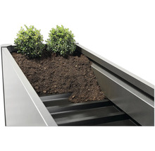 Prim-plan cu o jardinieră înaltă plantată cu pământ și plante