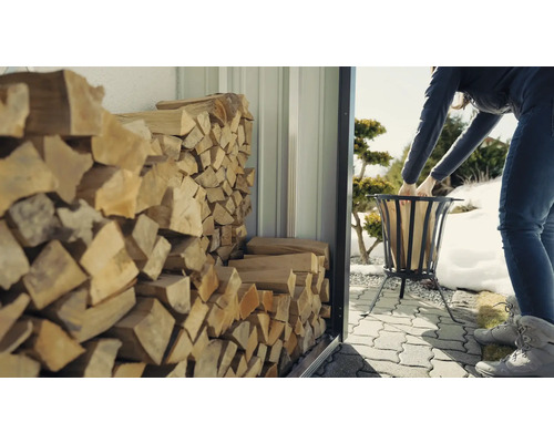 Femeie umplând coșul de foc cu lemne dintr-un adăpost pentru lemne