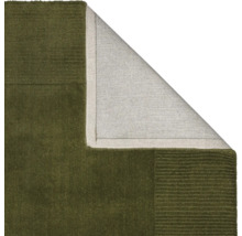 Vizualizare detaliată a unui covor verde cu un colț întors care arată partea din spate