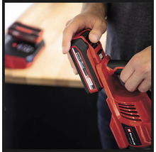 O persoană ține o unealtă roșie cu acumulator Einhell cu o baterie introdusă.